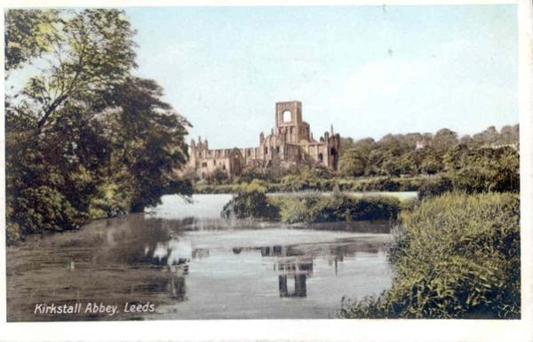 A tinted colour photograph of a river and trees with a ruined monastery in the background