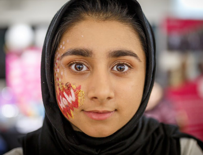 A young woman in a headscarf with her face painted.