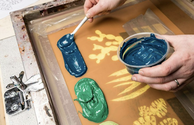 Blue and green inks being applied to a screen ready to print an image of plants