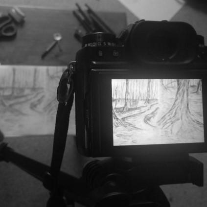 A black and white photo showing a camera displaying some drawn scenery