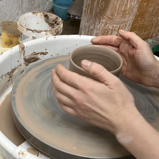 A pair of hands throwing on the potters wheel