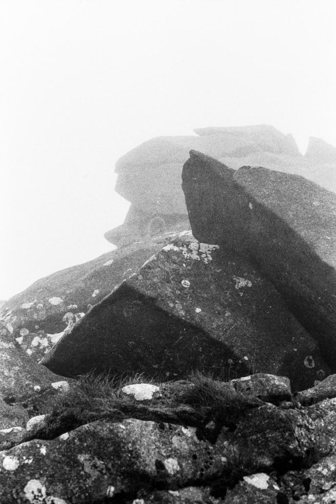 A black and white photograph of a rocky misty landscape.