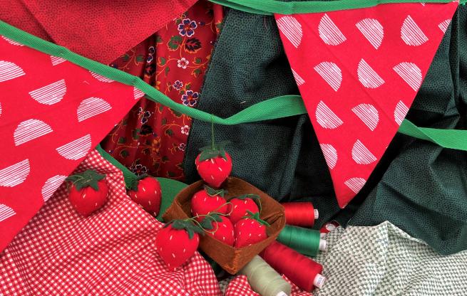 Red felt strawberries and red and green bunting in front of a red and green fabric background