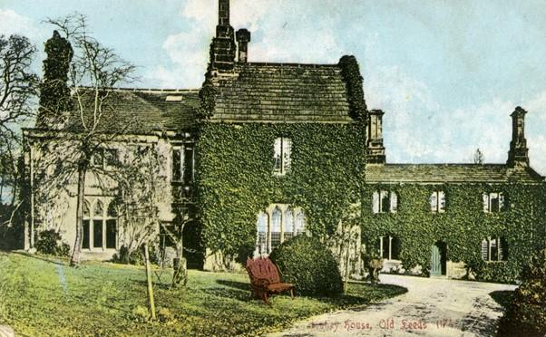 A tinted colour photograph of a house covered in ivy. 