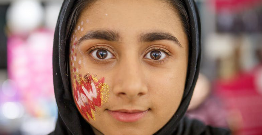 A young woman in a headscarf with her face painted.