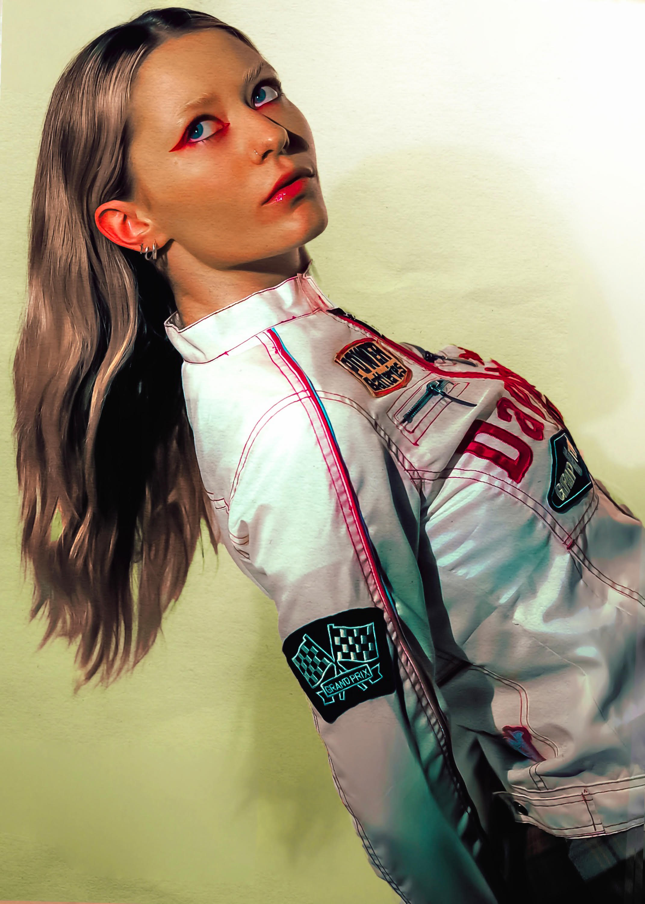  The artist Lois wearing a white biker jacket and styling graphic red eyeliner whilst leaning into the centre of the page