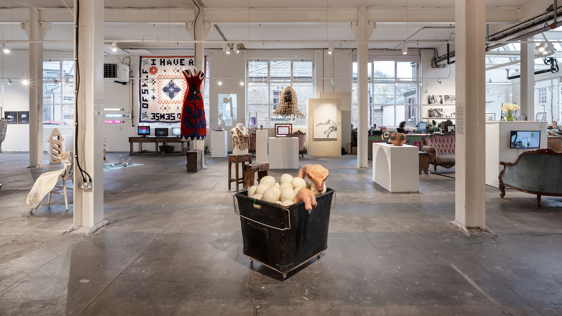 Wide-angle view of the Gallery, with a sculpture of an ostrich inside a laundry cart full of ostrich eggs positioned on the floor in the foreground.