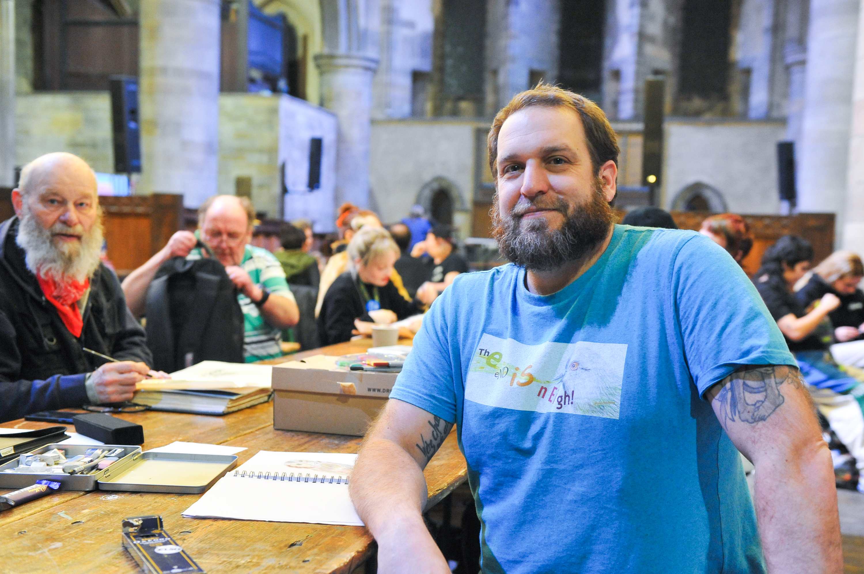 Edek, sat in a blue tshirt at a doodle chat event surrounded by attendees