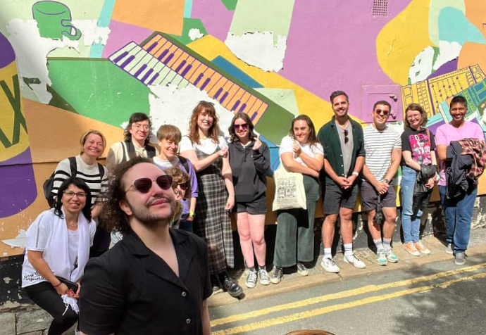 A group of people stand in front of a mural