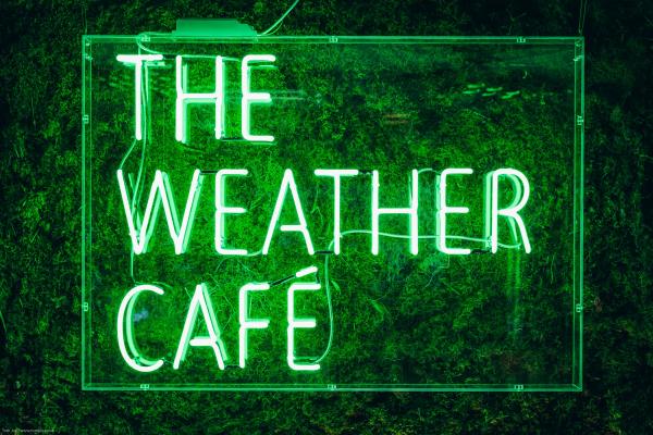 illuminated green sign of the words The Weather Cafe