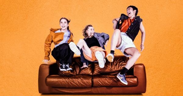 Three women jumping on a sofa while laughing.