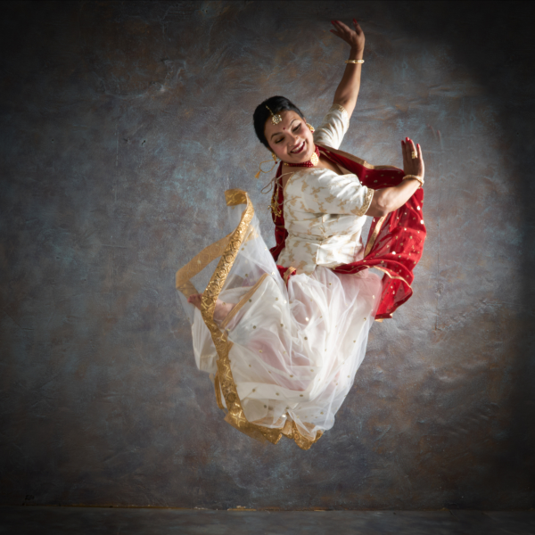 Person smiling as they jump with their arm outstretched.