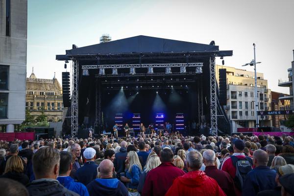 A band playing on the Summer Series stage in front of a crowd of people