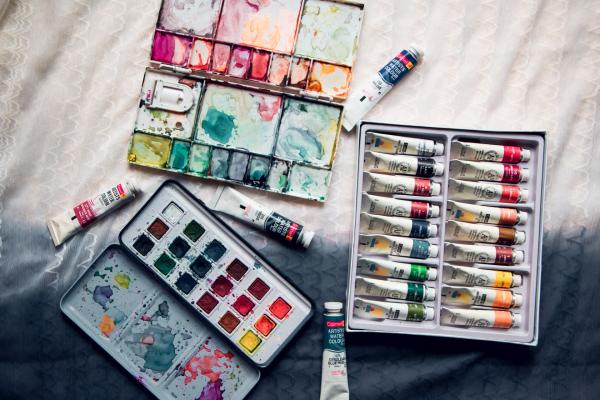 A set of watercolour paints and some watercolour pan sets are open on a table