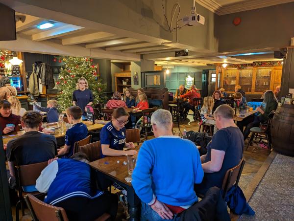 People sitting at tables playing boardgames. 