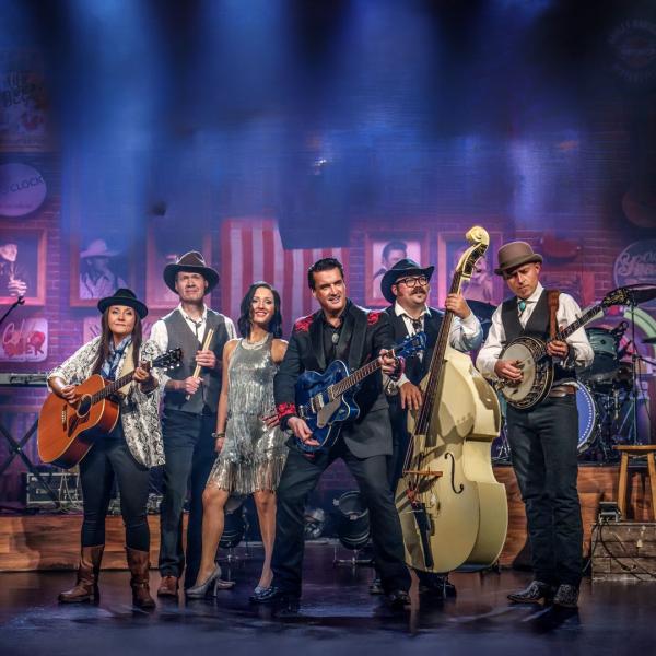 A Country night Nashville image with performers holding their instruments on stage, some wearing cowboy hats. An American flag appears in the background.