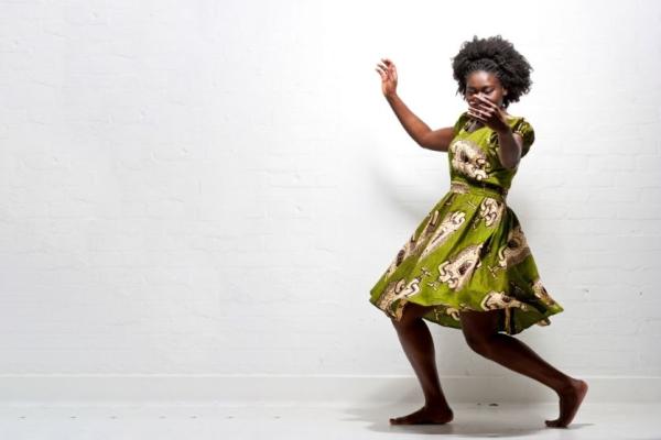 A person in a green patterned dress dancing joyfully