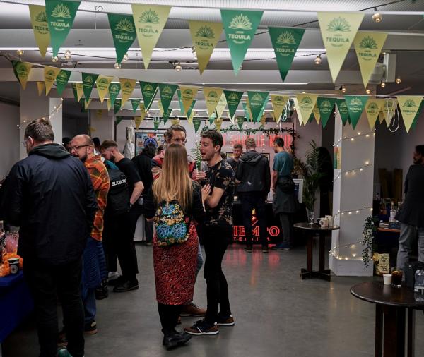 Group of people stood in white room with fairy lit pillars and green and white bunting