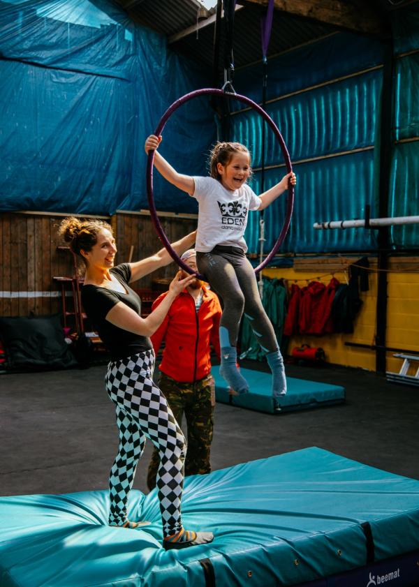 Photo of one of our students sitting inside an aerail hoop alongside our instructors