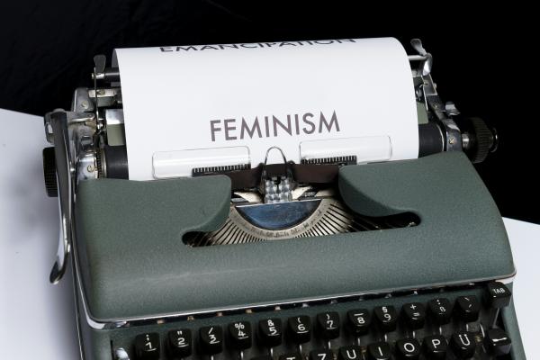 a typewriter with a sheet of paper in it spelling out FEMINISM