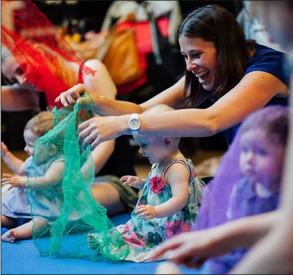 Image of babies and a parent playing with a silk scarf with their baby