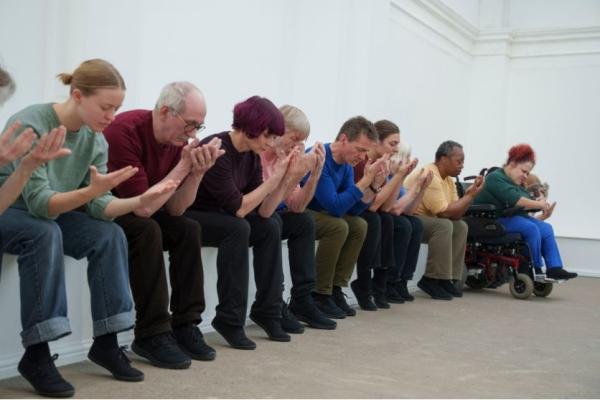 People sit in a row with heads in hands