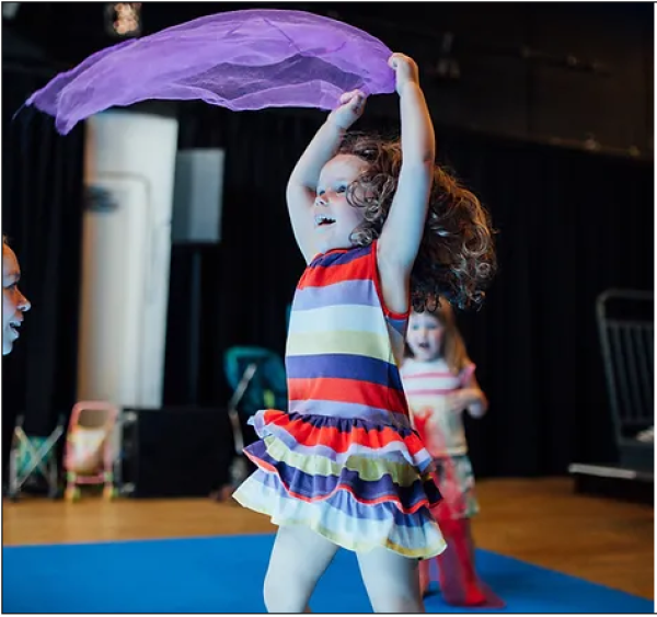 Image of a young girl twirling with a purple silk scarf