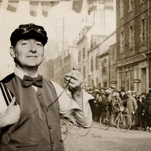 Sepia-toned photograph of Ned Boulting in 1920s dress including a waistcoat, bow tie and flat cap photoshopped into an actual 1920s street photo featuring someone on a bike.