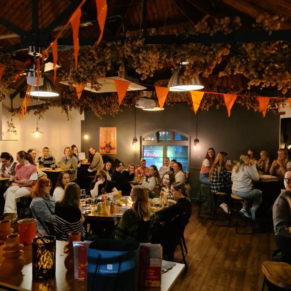 Group of women sat down around tables, in a cosy atmospheric environment.