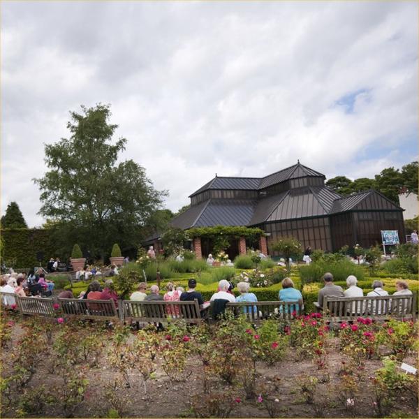People sat outside in a park watching a concert. 