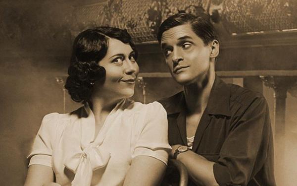 A sepia photo of two people sat beside each other.