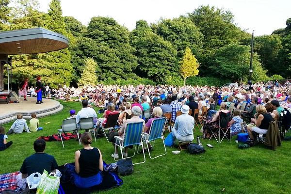 People sat in the park watching musicians perform.