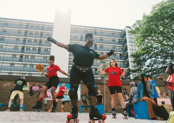A group of women dancing on rollerskates in a brightly coloured community garden