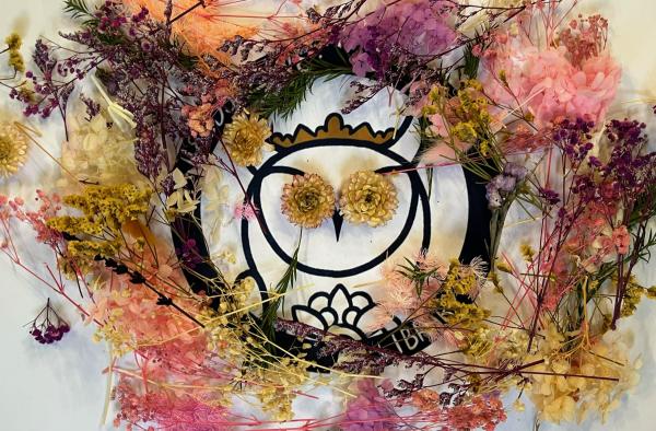 Owl logo covered in pink, purple and yellow flowers