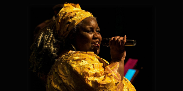 A person holding a microphone and dressed in yellow.