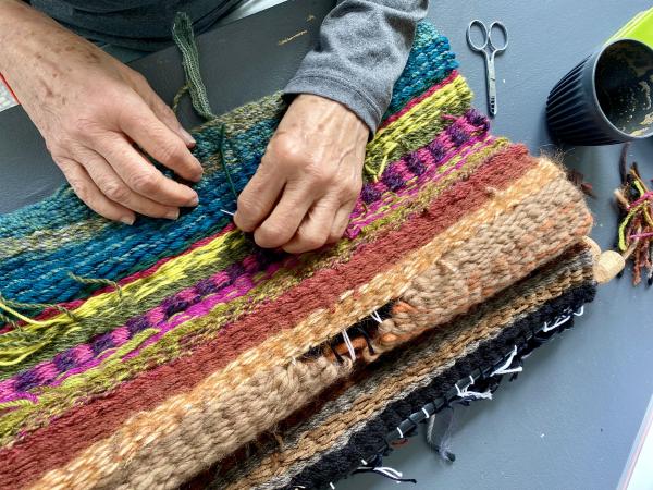 An image of woman's hands making a woven rug.
