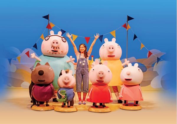 An actor stood on a stage with their arms in the air, surrounded by six animal puppets.