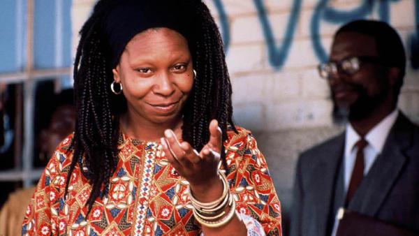 woman looks into camera with her hand raised
