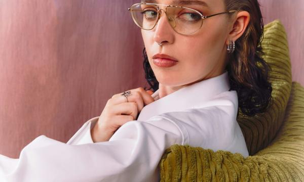 Gia Ford with glasses reclining on a seat