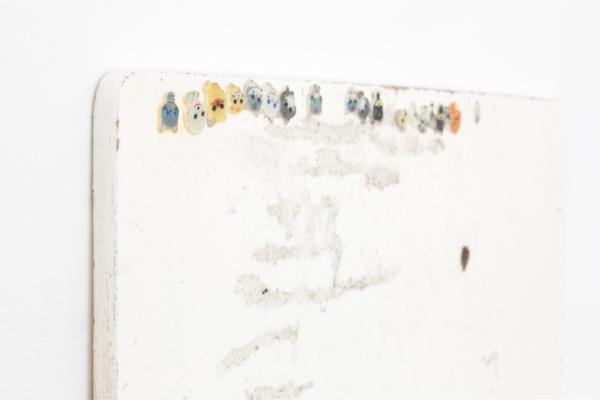 Close-up detail of a sculpture comprised of a piece of white board with upside-down stickers of cats on.