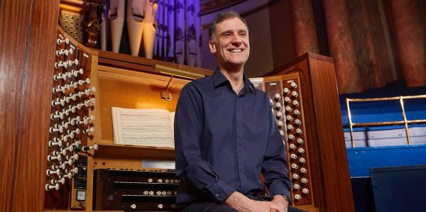 A musician sat on the organ bench looking into the distance.