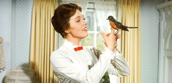 Julie Andrews, dressed smartly as Mary Poppins in a white blouse and red bow, has a robin perched on her finger.