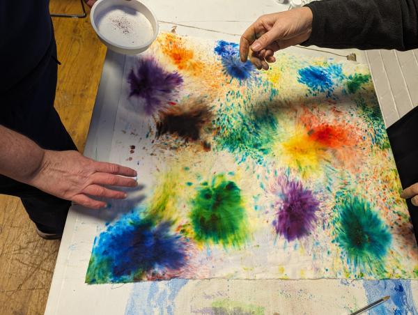 a coulorful artwork with two hands working on it
