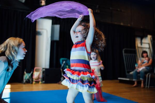 An image of a young girl twirling around with a purple silk scarf