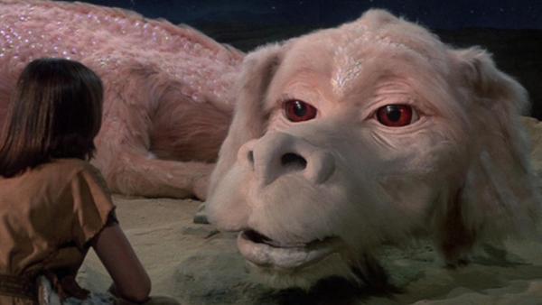 A young boy looks into the eyes of giant white LuckDragon, Falcor.