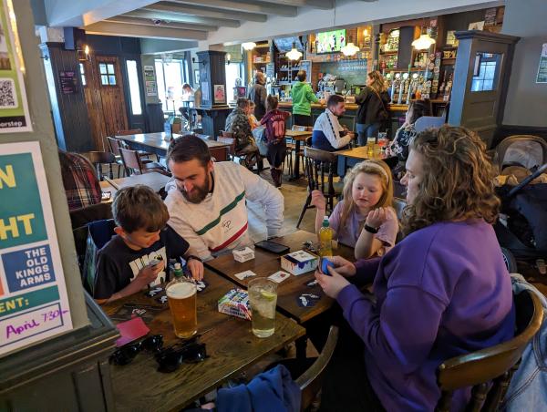 A family sitting at a table in a pub playing a game.