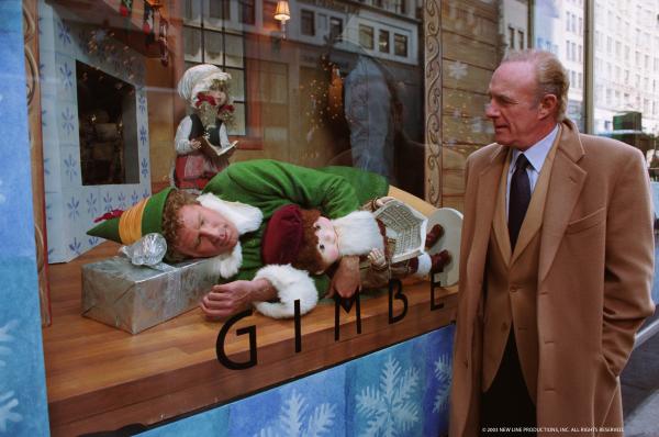 Image shows Elf asleep inside a shop window with a man staring through the window