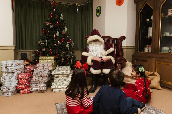 Father Christmas surrounding by presents at Temple Newsam with children in the foreground