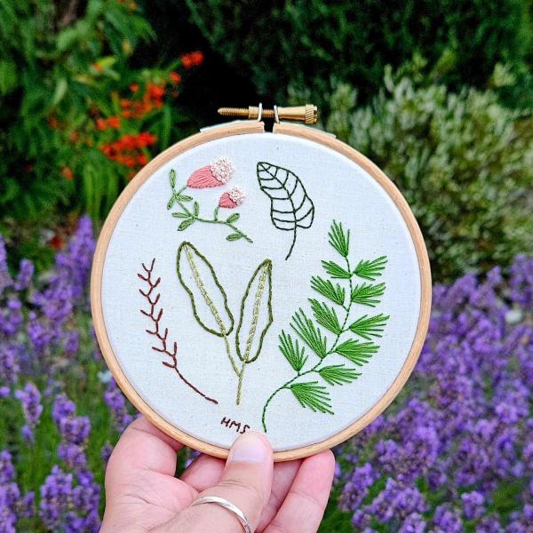 Hand holding embroidery hoops with embroidered flowers