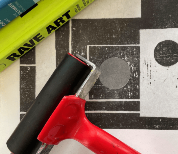 Ink roller on top of a black and white print of squares and circles.